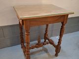 une petite table en bois avec un plateau en verre, posée à même le sol