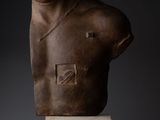 a sculpture of a man ' s torso is shown against a dark background