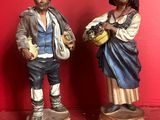 two figurines of a man and a woman standing next to each other