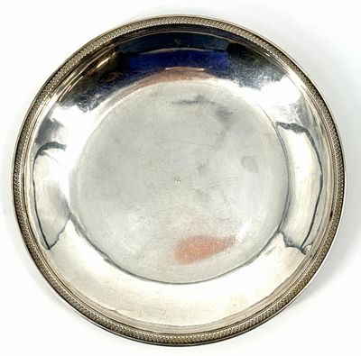 une assiette en argent posée sur une surface blanche avec un fond bleu