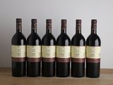 six bouteilles de vin rouge alignées sur une table en bois