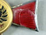 a red and gold cross with a black eagle on it