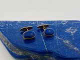 deux paires de boutons de manchette bleus et dorés posés sur un galet bleu