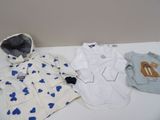 trois vêtements de bébé posés sur une table blanche