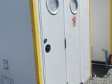 two white and yellow portable toilets in a parking lot