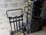 a stack of boxes and a hand truck next to a brick wall