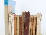 several old books are stacked on top of each other on a white surface