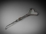 a silver spoon with a heart shaped handle on a gray surface