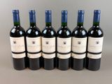 six bouteilles de vin sont alignées sur une table