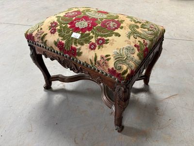 un petit repose-pieds avec une assise rembourrée à motifs floraux