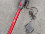 a red and black corded vacuum on the ground