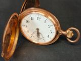 une montre de poche en or posée sur une surface noire