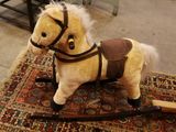 un cheval en peluche posé sur un tapis au sol