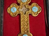 une croix en or richement décorée, sertie de pierres bleues, dans un coffret rouge