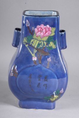un vase bleu orné d'une fleur rose