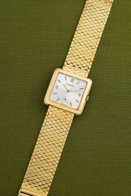 a close up of a gold wrist watch on a green surface