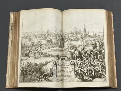 an open book with a drawing of a city in the background