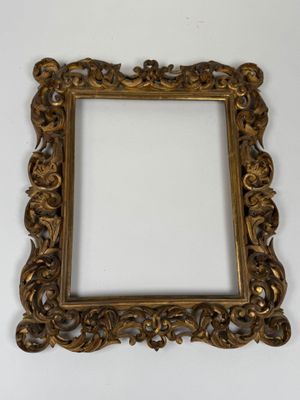 an ornate gold frame with a white background and a white wall