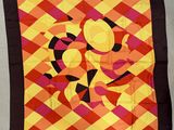 une image représentant un foulard carré orné d'un motif de couleurs orange et jaune sur fond noir