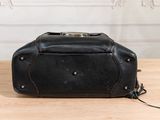 black leather purse on a wooden table with a white wall in the background