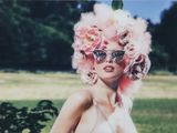 une femme portant une perruque rose et des lunettes de soleil, en train de poser pour une photo