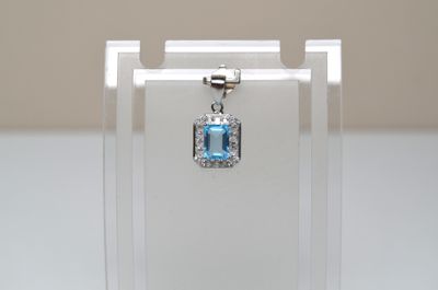 un petit pendentif en cristal bleu présenté dans une vitrine transparente