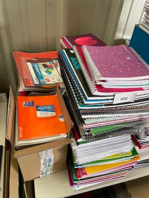 une pile de livres sur un bureau, à côté d'un tas de classeurs