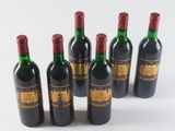 six bottles of wine are lined up in a row on a white surface
