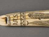 an image of an elephant tooth with carvings on it on a gray surface