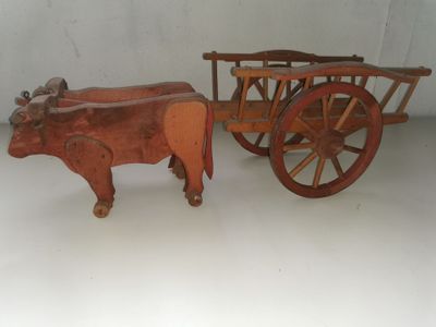 un jouet en bois représentant une vache tirant une charrette sur laquelle se trouve une autre vache