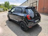 the rear end of a small black car parked in a parking lot