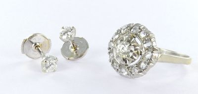a close up of a diamond ring and earring on a white surface