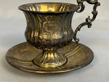 an antique silver cup and saucer on a saucer on a table