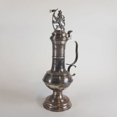 une cafetière ancienne en métal argenté, surmontée d'un oiseau