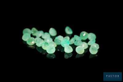 a close up of a bunch of green gems on a black surface