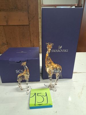 two figurines of giraffes on a table next to a blue box