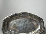 an antique silver plate with a decorative edge on a table
