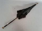 un parapluie noir posé par terre sur une surface blanche