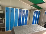 a bed in the middle of a room with blue lockers