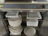de nombreuses assiettes et casseroles empilées sur une étagère dans la cuisine