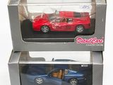 une paire de petites voitures moulées sous pression, rouge et bleue, dans leurs boîtes, posées sur une surface blanche