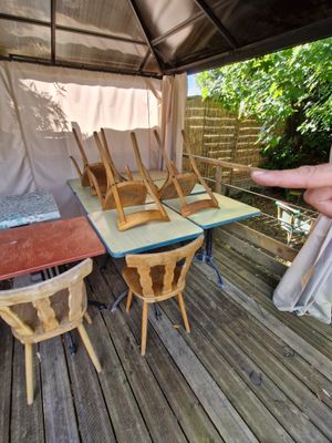 a person pointing at a table and chairs on a deck