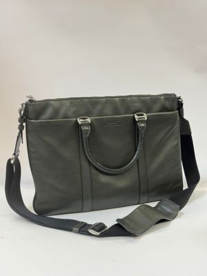 a green leather bag with a black strap on a white background