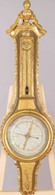 une horloge dorée posée sur un socle en bois, sur fond gris