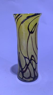 un vase jaune orné d'un tourbillon noir