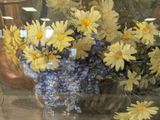 yellow and blue flowers in a glass vase on a window sill