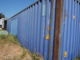 a blue shipping container sitting on the side of the road