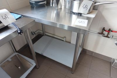 une table en acier inoxydable sur laquelle sont posés des casseroles et des poêles