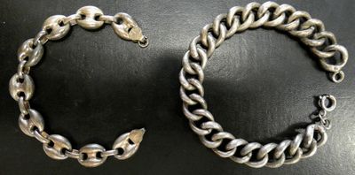 a close up of two silver bracelets on a black surface