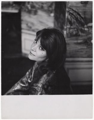 photographie en noir et blanc d'une femme assise devant une cheminée